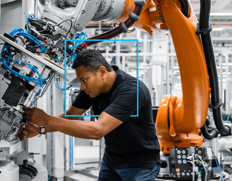 An engineer works on a robotic arm in a modern manufacturing environment.